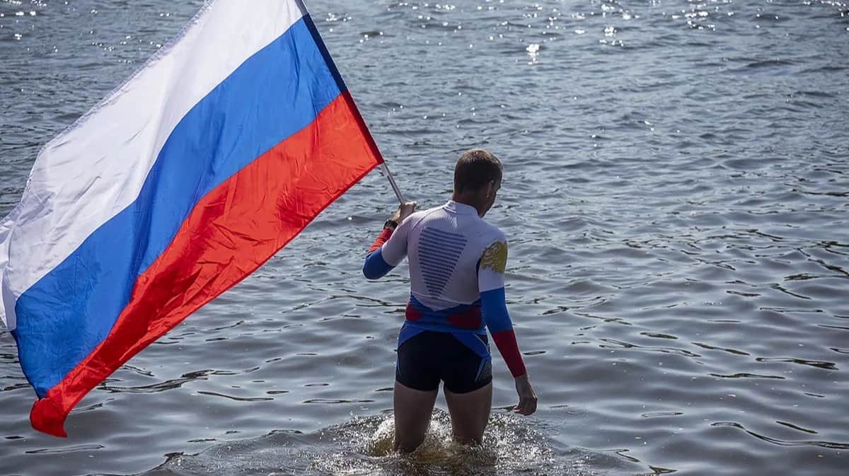 Пловец с российским триколором заходит в воду. Фото: Дмитрий Цыганов