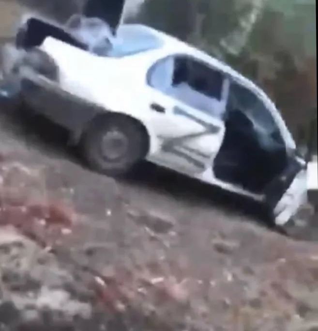В кадре заметны два гражданских автомобиля белого цвета — на одном из них черным нарисована большая буква «Z». Фото: скрин видео