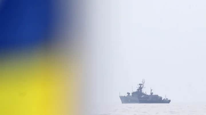 A Ukrainian flag flies on land as a Russian Navy corvette sails along the Black Sea coast near Sevastopol amid the Russian annexation of Crimea, 2 March 2014. Photo: EPA / MAXIM SHIPENKOV