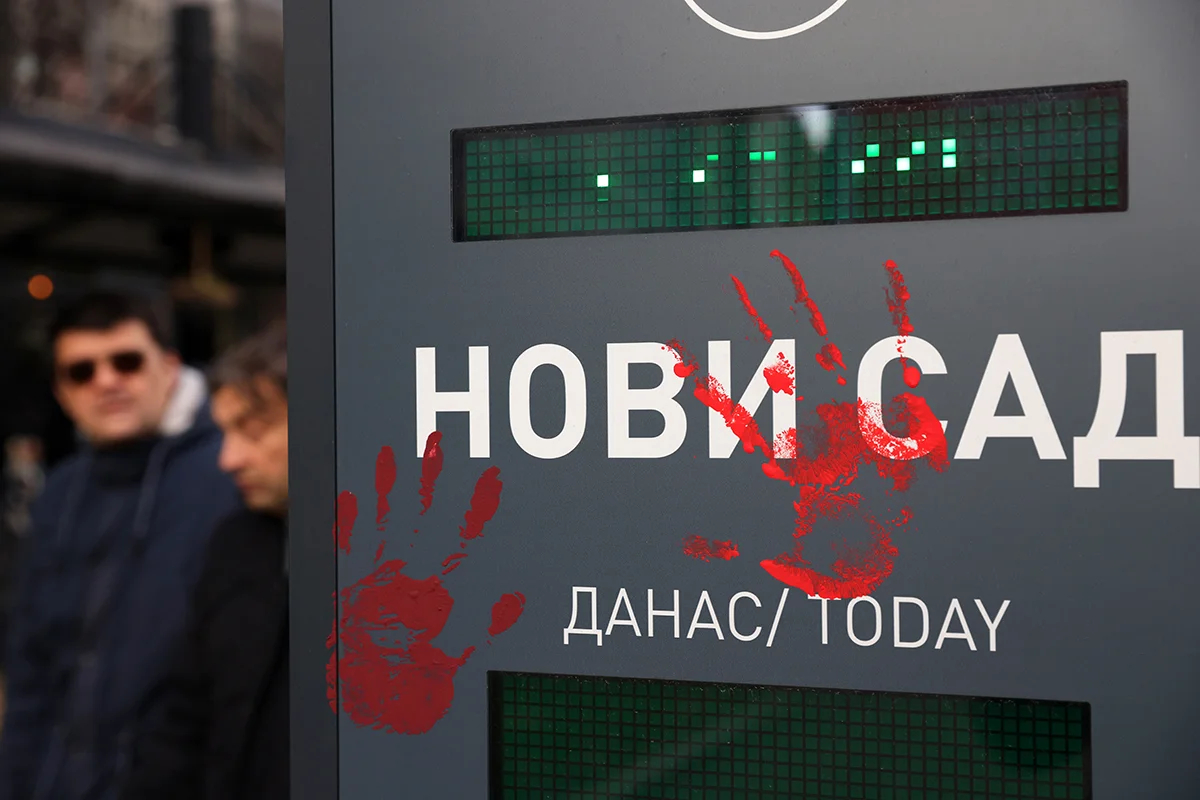 Люди проходят мимо изображений окровавленных рук во время месячной годовщины аварии на железнодорожном вокзале в Нови-Саде, Сербия, 1 декабря 2024 года. Фото: Andrej Cukic / EPA-EFE