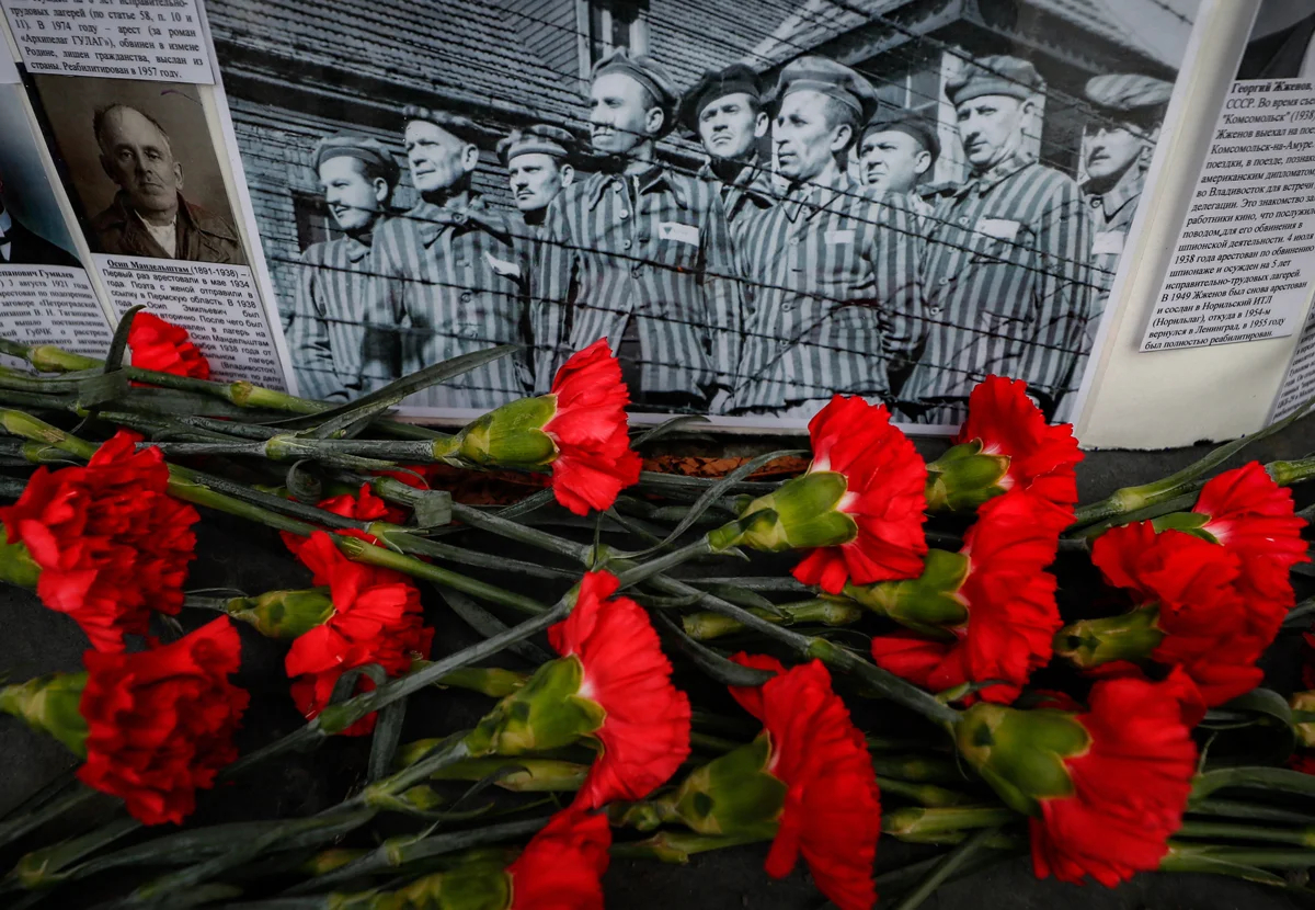 Цветы перед фотографией заключённых у мемориала «Стена скорби» в Москве, 30 октября 2020 года. Фото: Юрий Кочетков / EPA