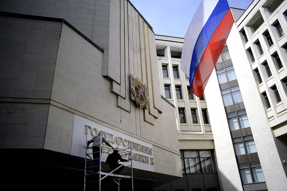 Рабочие заменяют украинскую надпись «Верховный Совет Автономной Республики Крым» на здании крымского парламента на российскую «Государственный Совет Республики Крым», Симферополь, Крым, Украина, 19 марта 2014 года. Фото: Jakub Kaminski / EPA