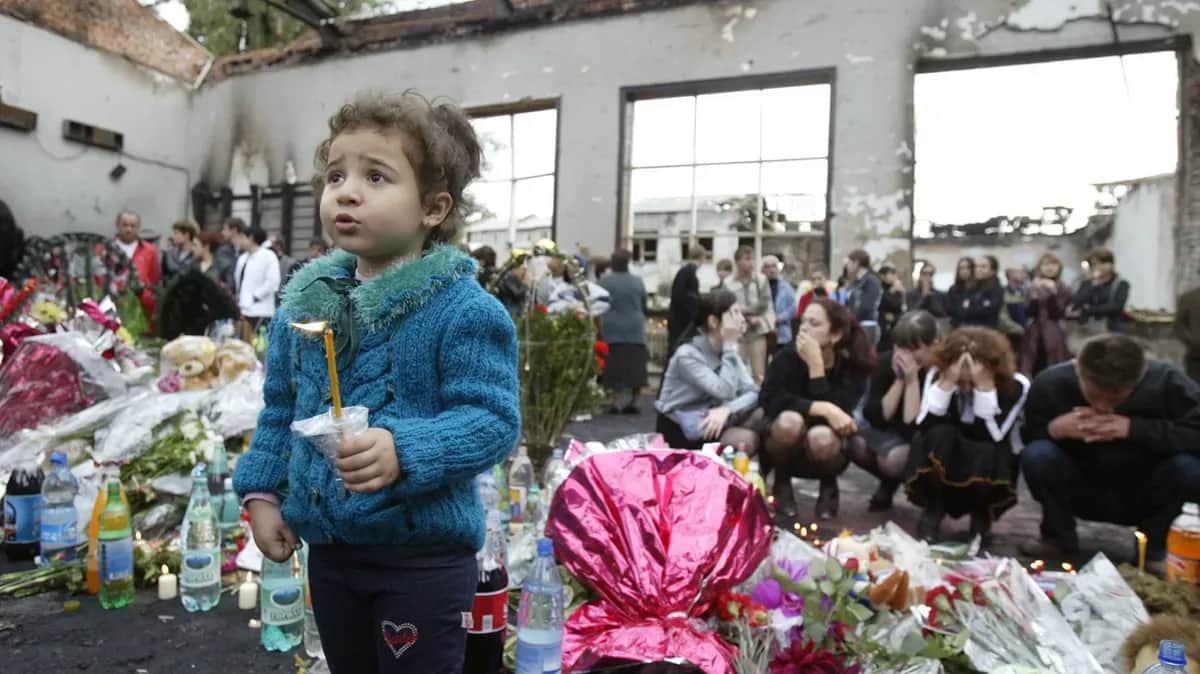 A young girl holds a candle in the ruins of School No. 1's gymnasium in Beslan, North Ossetia, 7 September 2004. Photo: EPA / YURI KOCHETKOV