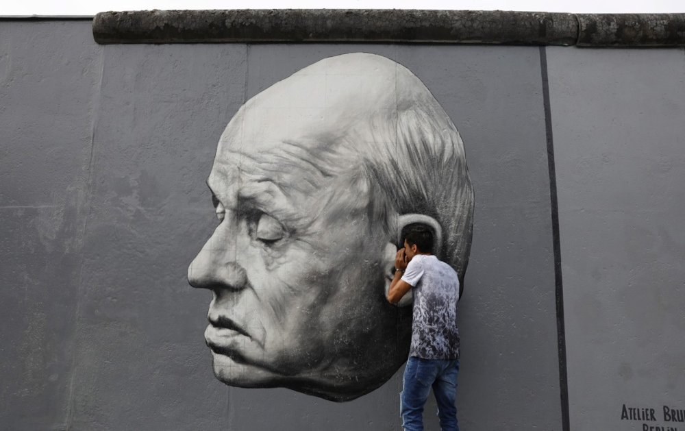 A tourist poses in front of the artwork Thank You Andrei Sakharov by Russian artist Dmitri Vrubel at the East Side Gallery in Berlin, Germany, 19 August 2017. Photo: EPA/ABIR SULTAN