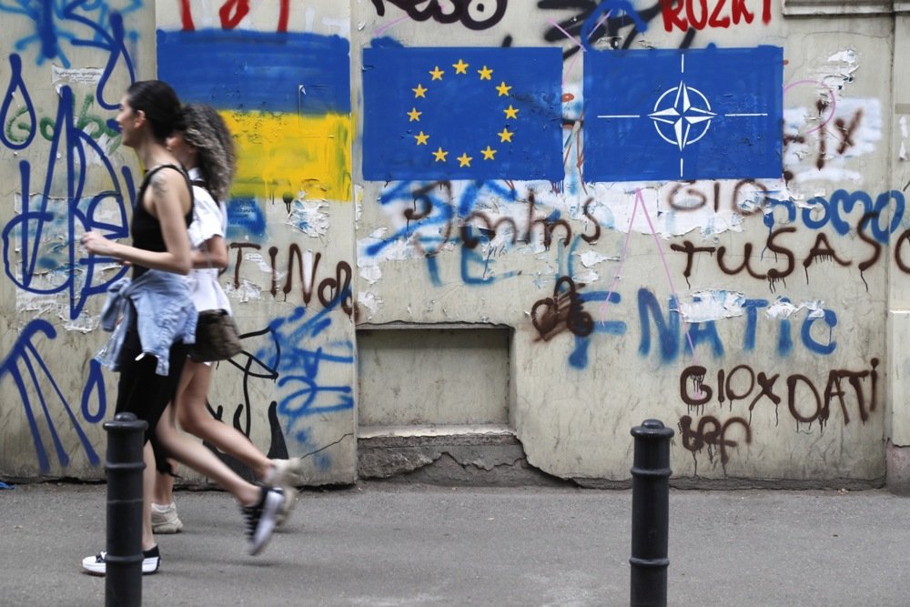 Two women walk past graffiti of the Ukrainian, EU and NATO flags in Tbilisi’s old town, 22 May 2023. Photo: EPA-EFE/ZURAB KURTSIKIDZE