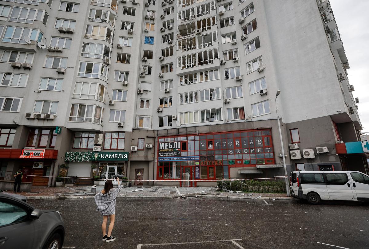 A residnent photographs an apartment block that was struck by a Russian drone in Kyiv, Ukraine, 28 July 2025. Photo: EPA / SERGEY DOLZHENKO
